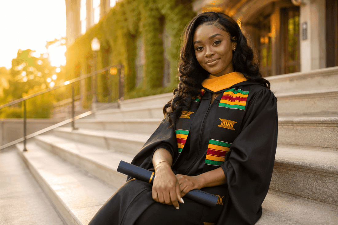African graduate in cap and gown holding her diploma