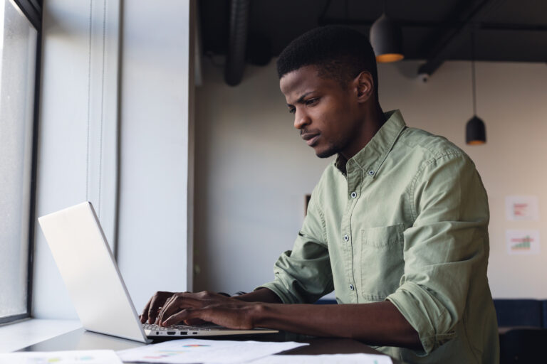 Determined african american young businessman working on laptop in creative office. Unaltered, creative business, workplace, wireless technology, concentration